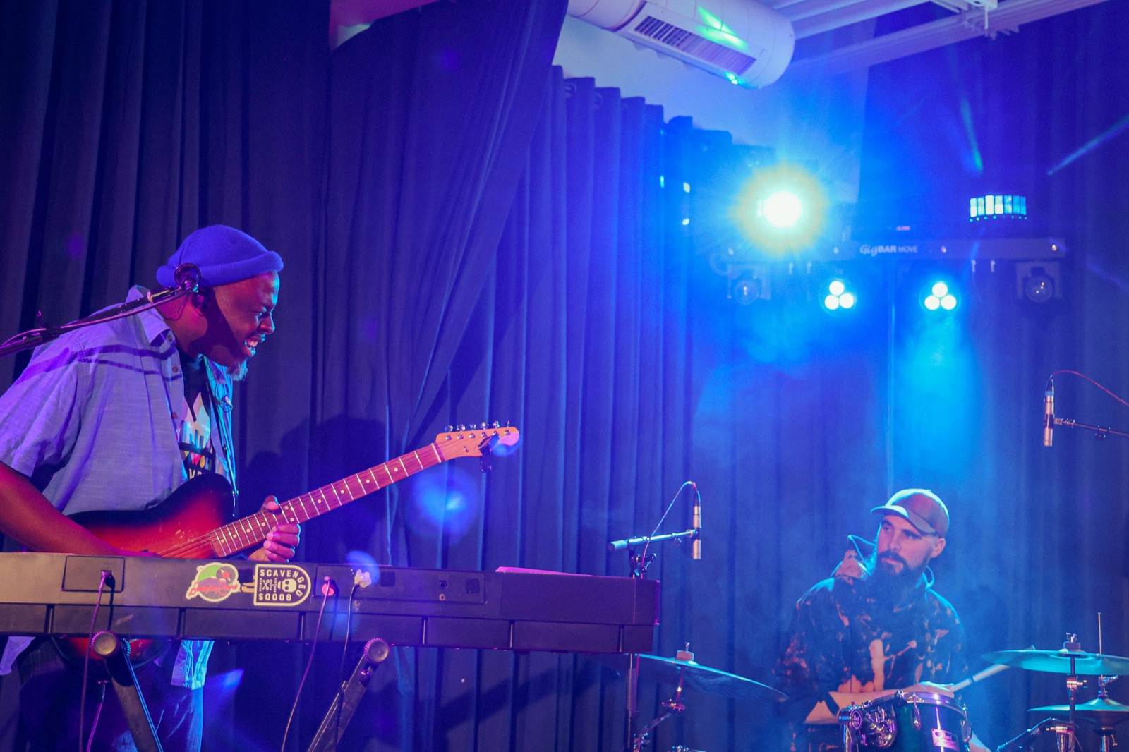 Felix Ayodele on keys and guitar under blue stage lights