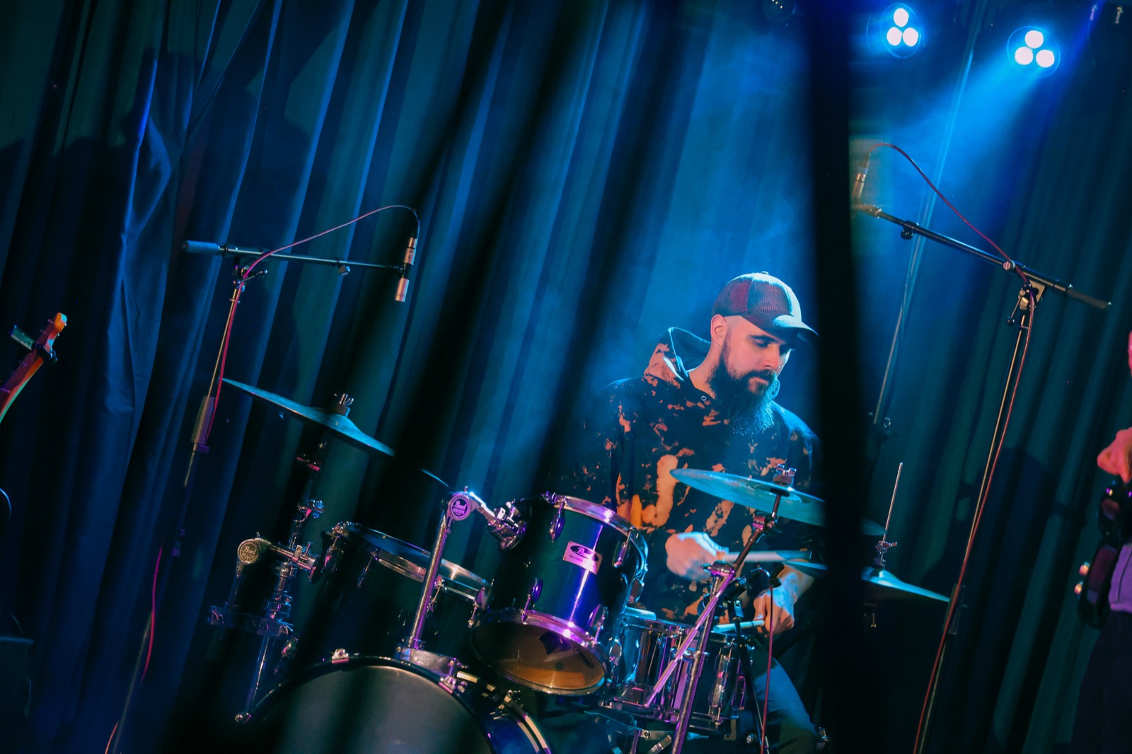 Drummer Peter Roach mid-performance in blue stage light